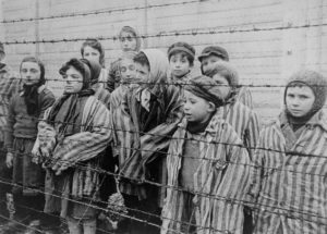 black and white photo of children standing in a concentration camp during the Holocaust era
